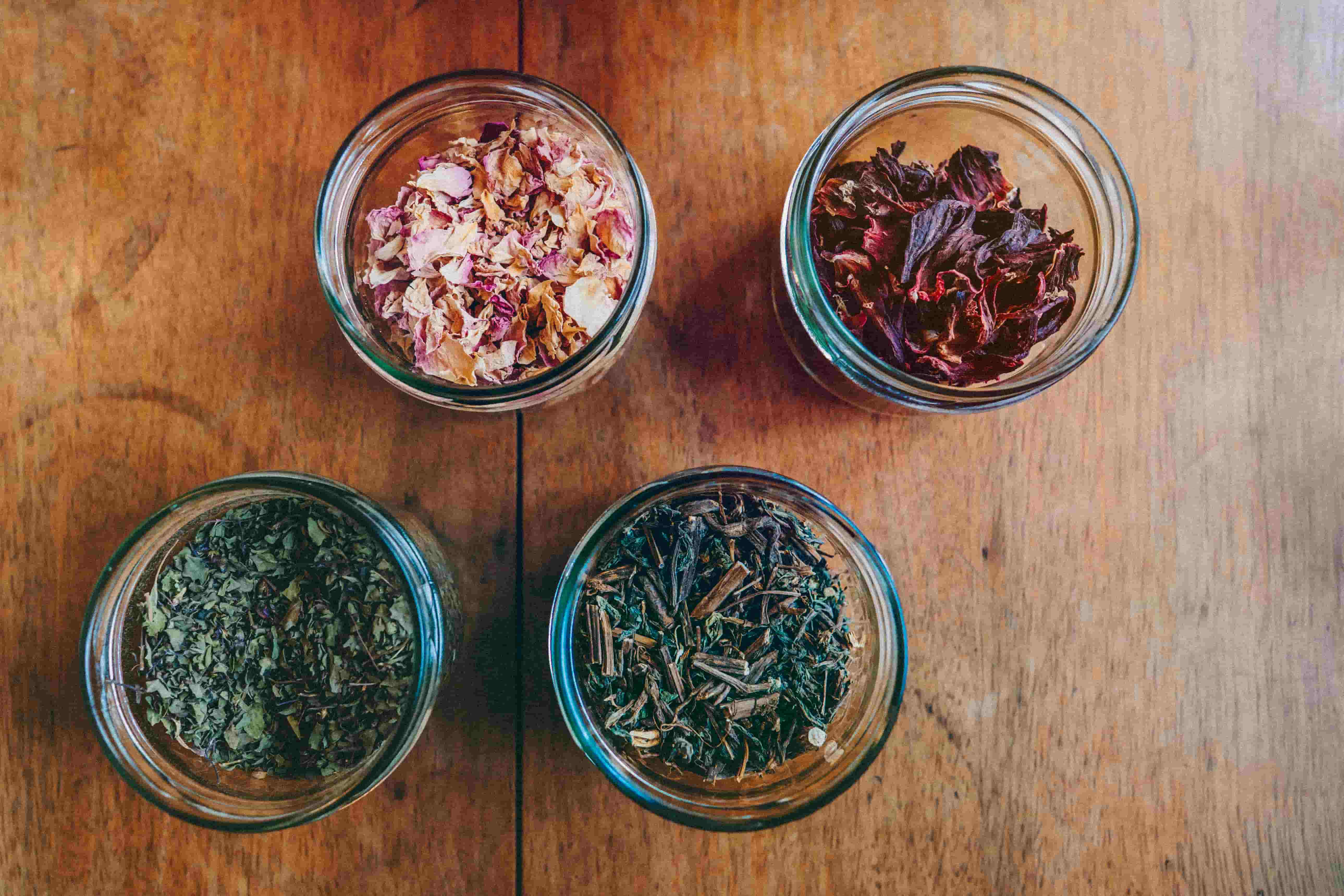 Jars of dried herbs and flowers on a wooden table
