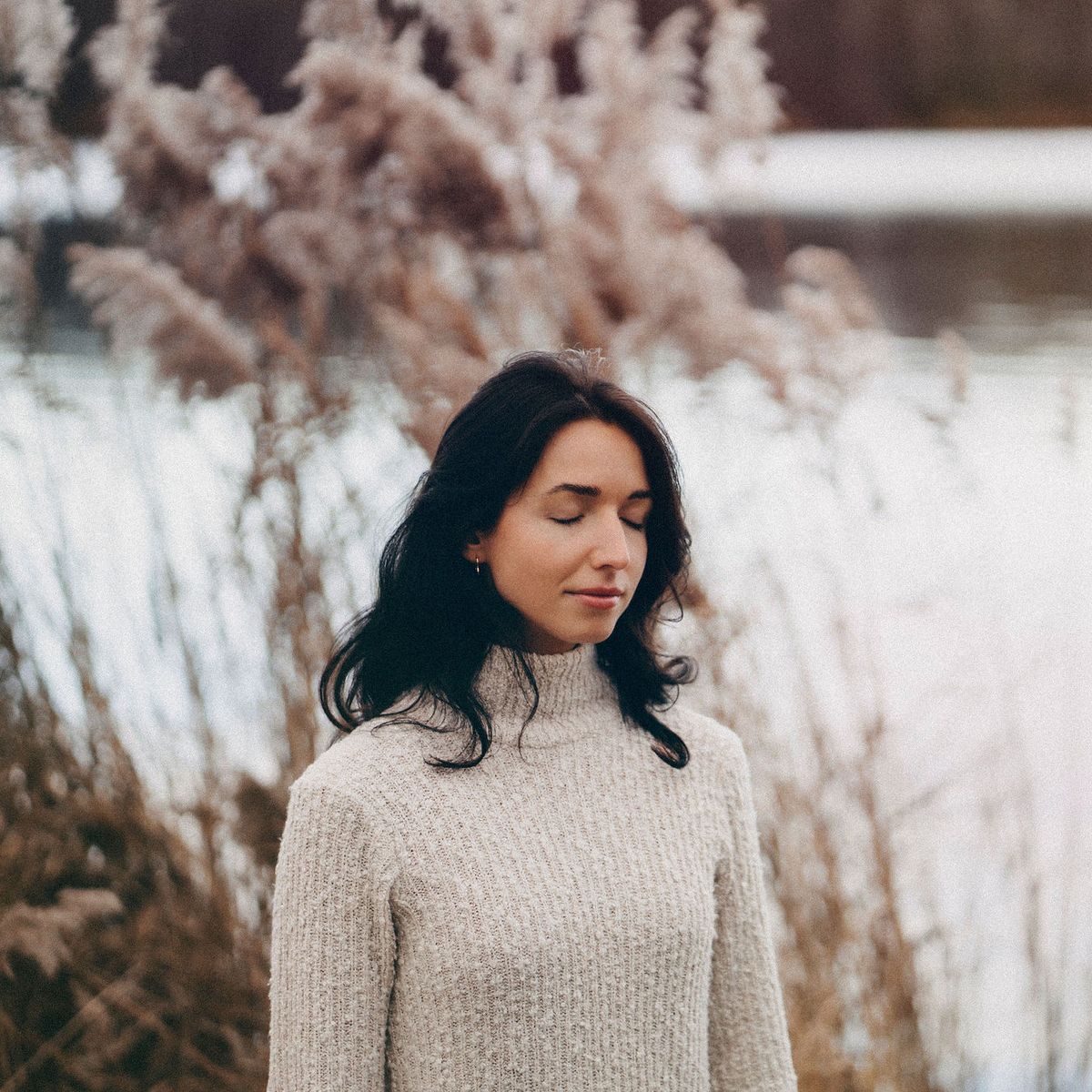 Zsofia standing by a lake with her eyes closed